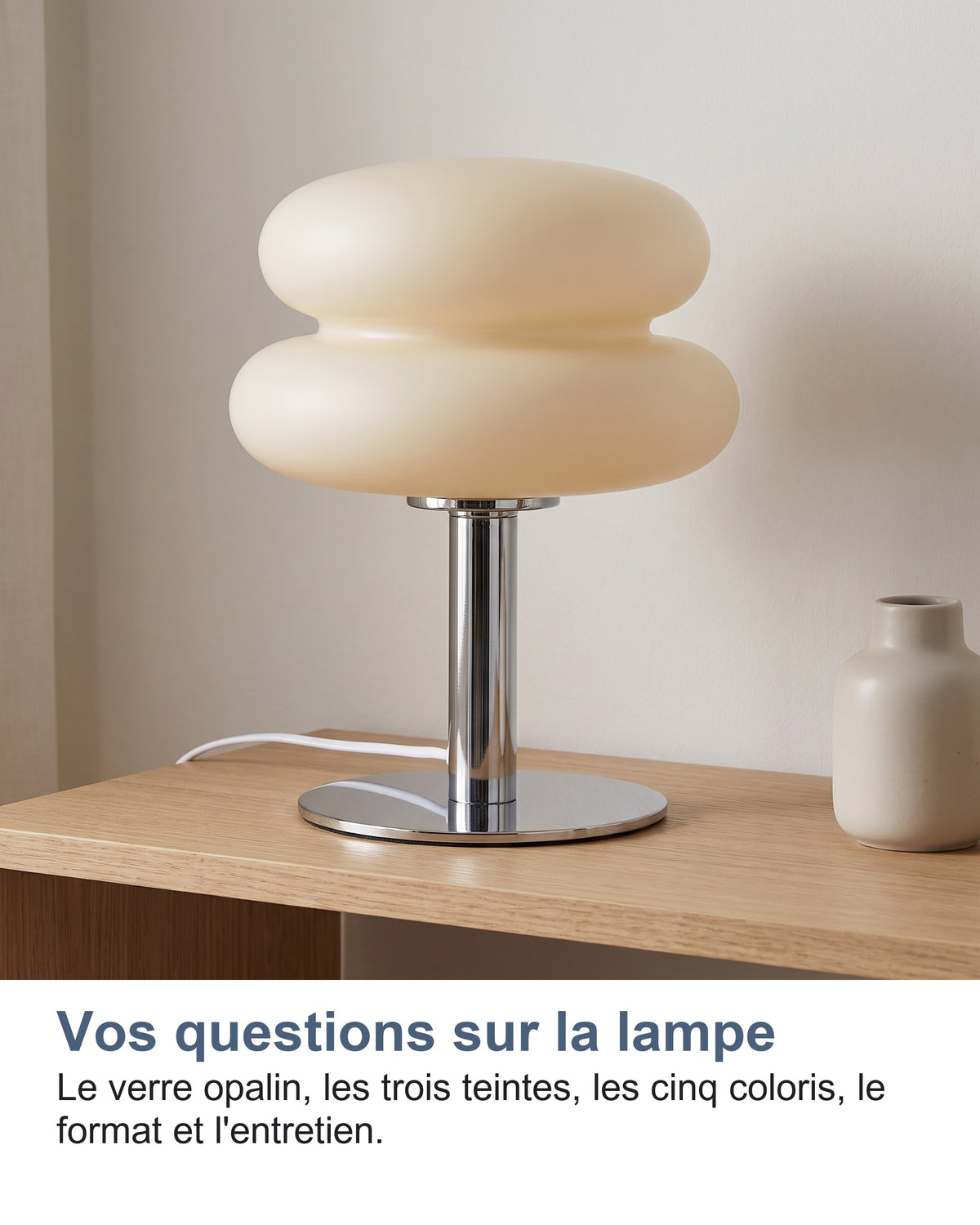 La lampe allumée sur une console en bois clair devant un mur nu