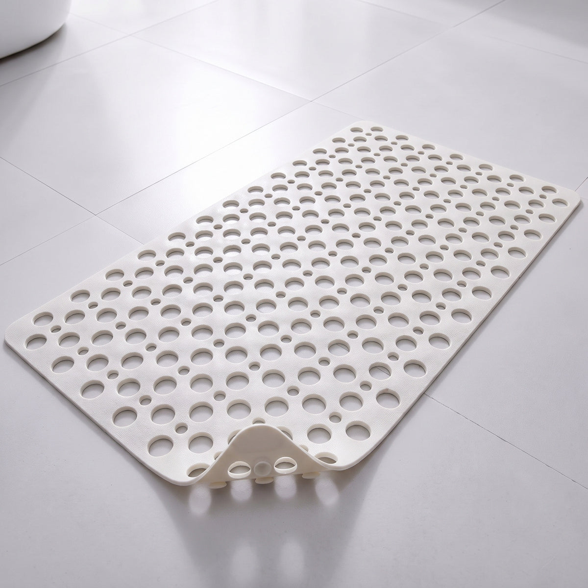 Tapis de douche antidérapant blanc à trous et ventouses, posé à plat sur un sol carrelé