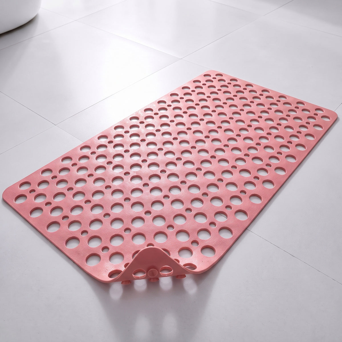 Tapis de douche antidérapant rose à trous et ventouses, posé à plat sur un sol carrelé