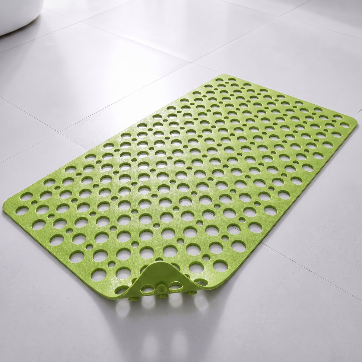 Tapis de douche antidérapant vert à trous et ventouses, posé à plat sur un sol carrelé