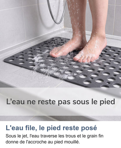 Pieds sur le tapis sous la douche, l'eau et la mousse passent par les trous