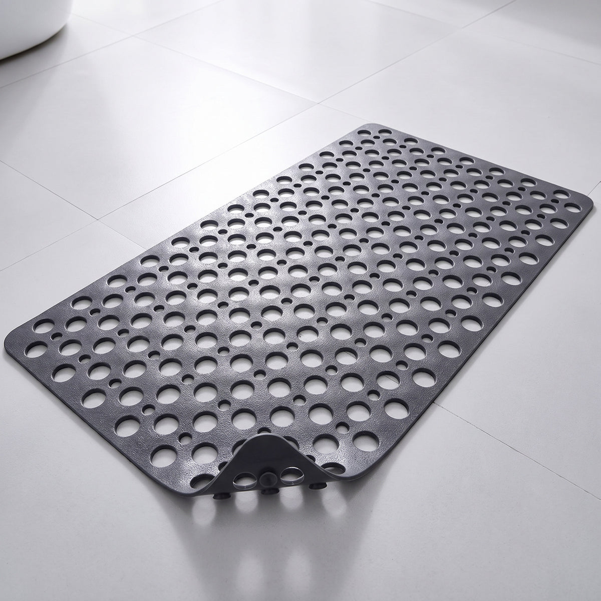 Tapis de douche antidérapant gris à trous et ventouses, posé à plat sur un sol carrelé
