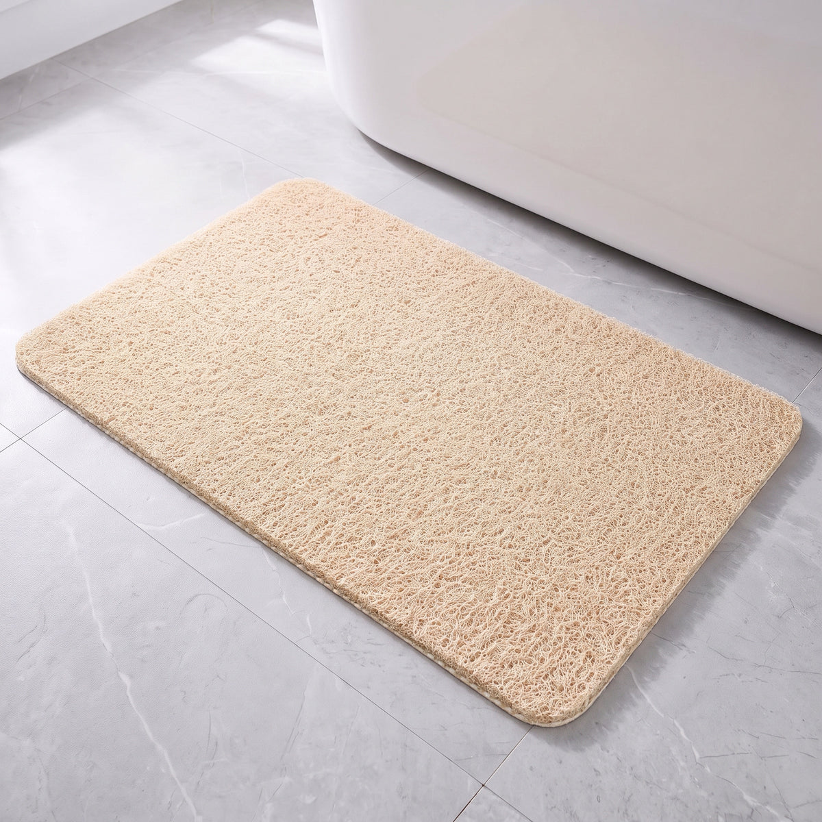 Tapis de bain antidérapant beige à boucles, posé à plat devant une baignoire