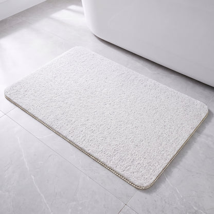 Tapis de bain antidérapant blanc à boucles, posé à plat devant une baignoire