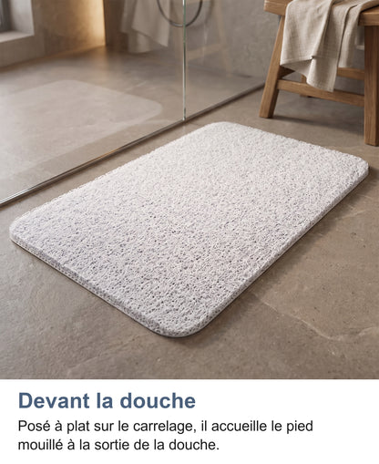 Tapis blanc posé devant une paroi de douche vitrée