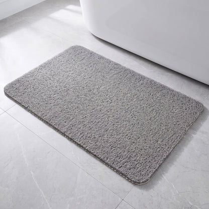 Tapis de bain antidérapant gris à boucles, posé à plat devant une baignoire