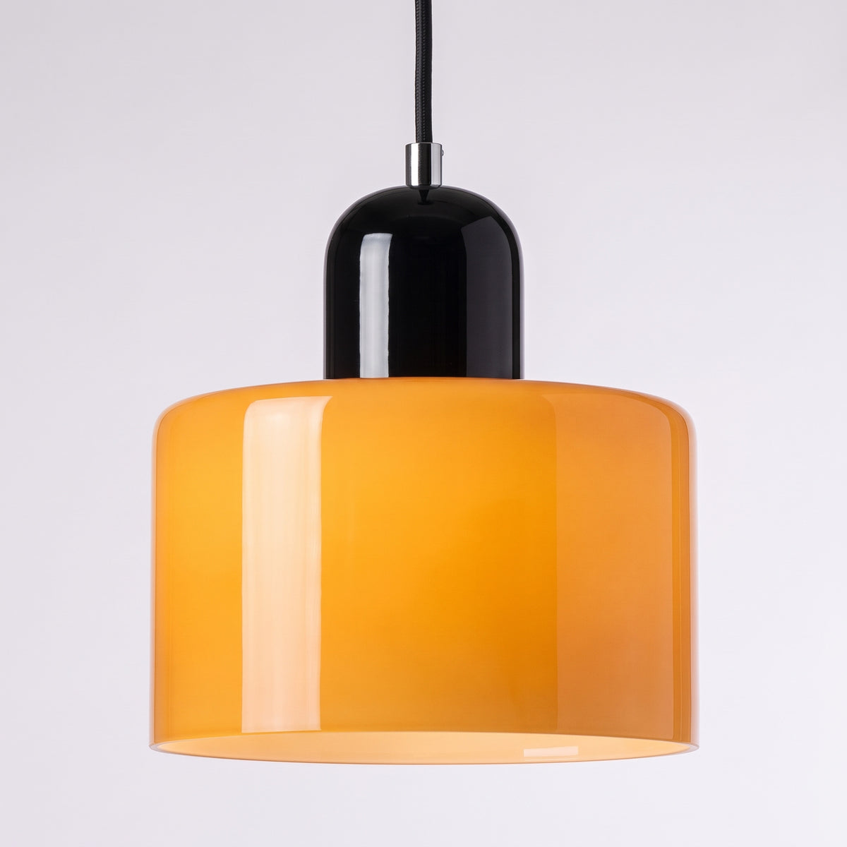 Suspension en verre à abat-jour cylindrique orange et chapeau laqué noir, sur fond gris clair