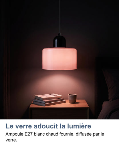 Suspension à abat-jour rose allumée au-dessus d'une table de chevet la nuit