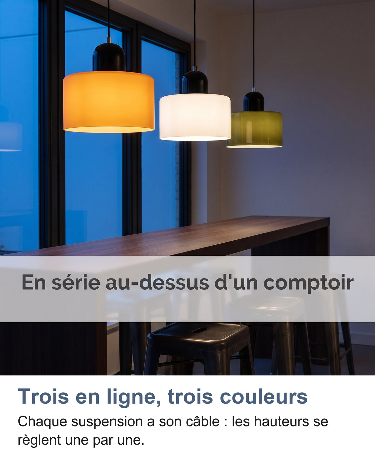Trois suspensions orange, blanche et vert foncé allumées au-dessus d'un comptoir au crépuscule