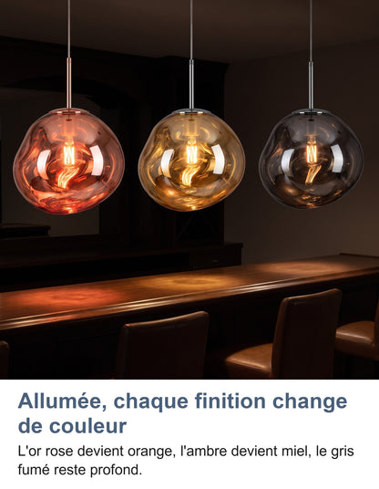 Trois suspensions allumées au-dessus d'un bar la nuit : or rose, ambre et gris fumé
