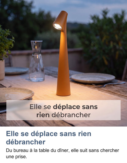 Lampe orange allumée sur une table de terrasse le soir