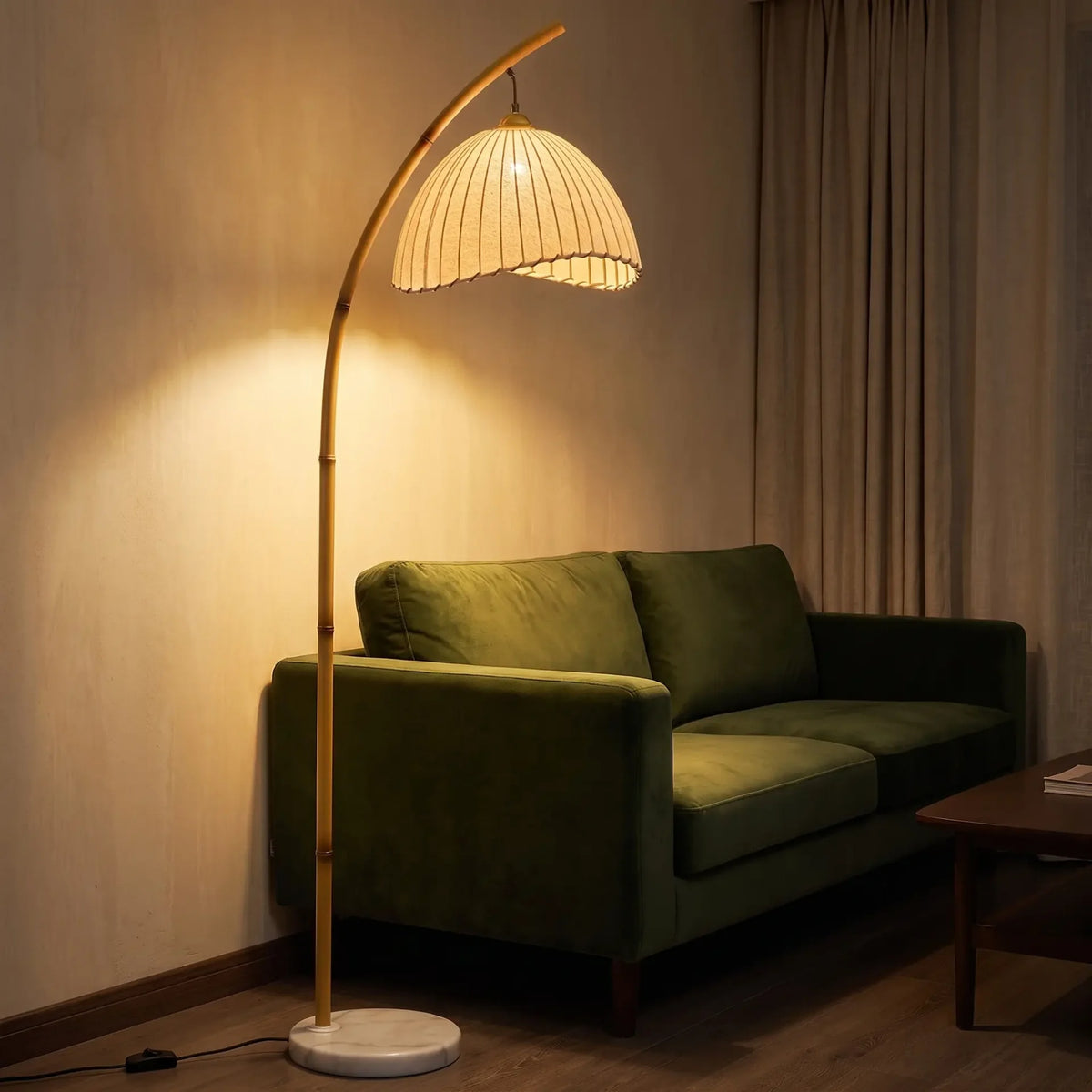 Lampadaire arqué allumé dans un salon, abat-jour plissé crème et base en marbre