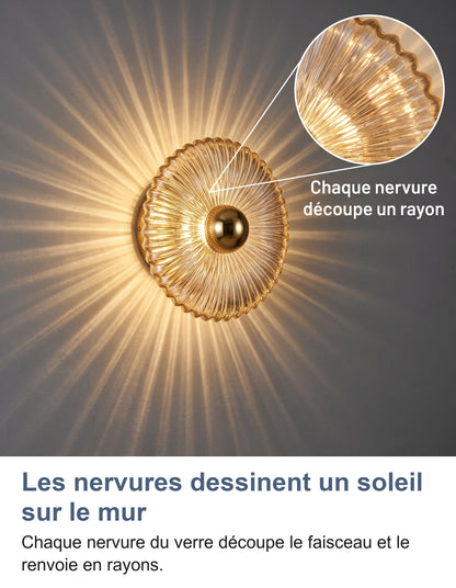 Applique en verre cognac allumée, rayons sur le mur et zoom sur les nervures du verre