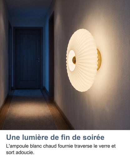 Applique en verre blanc de lait allumée dans un couloir sombre la nuit