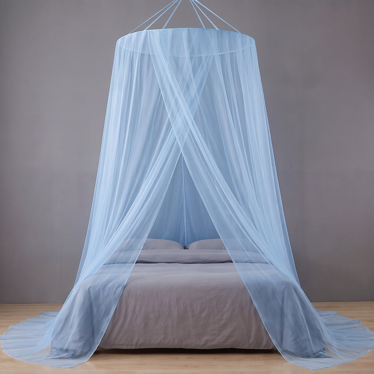 Moustiquaire de lit en dôme bleue suspendue au-dessus d'un lit double, ourlet étalé au sol