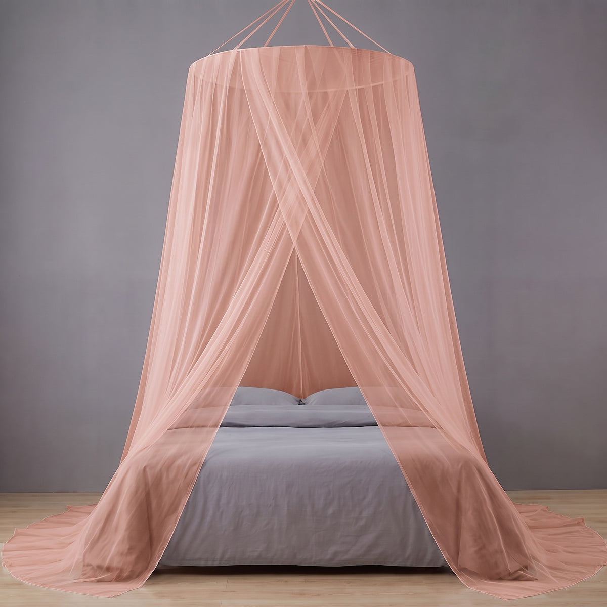 Moustiquaire de lit en dôme rose suspendue au-dessus d'un lit double, ourlet étalé au sol