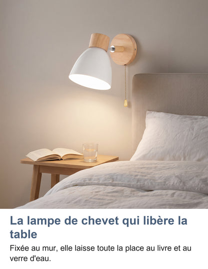 Applique murale blanche allumée au-dessus d'une table de chevet, livre ouvert et verre d'eau