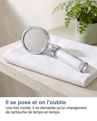 Le pommeau de douche filtrant posé sur une serviette