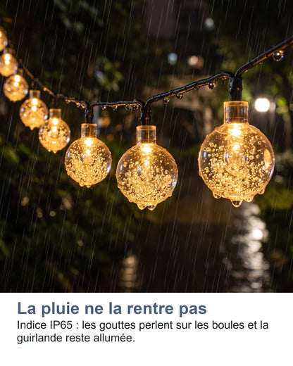 La pluie ne la rentre pas Indice IP65 : les gouttes perlent sur les boules et la guirlande reste allumée.