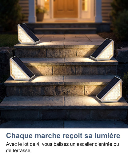 Quatre spots solaires allumés sur les marches d'un jardin au crépuscule