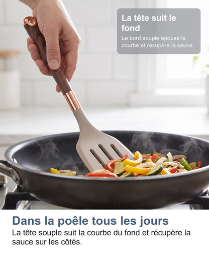 La spatule ajourée retourne des légumes dans une poêle chaude