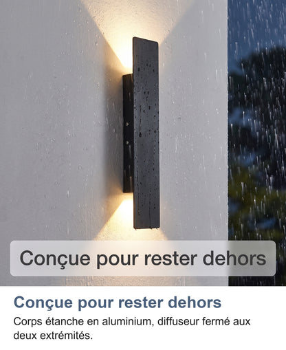 Applique noire allumée sous la pluie sur un mur extérieur