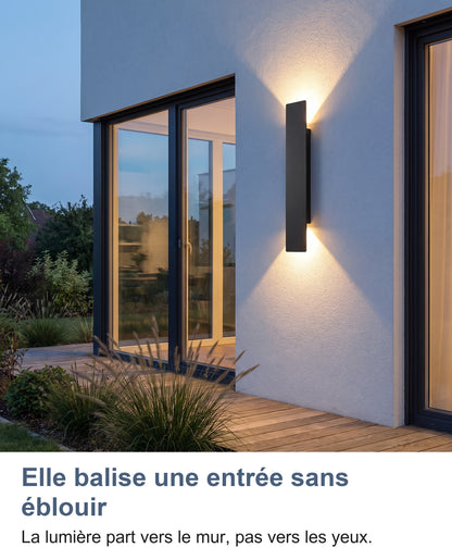 Applique noire allumée à côté d'une porte-fenêtre de terrasse au crépuscule